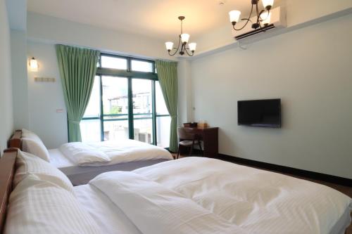 a bedroom with two beds and a tv and a window at Rgb in Hualien City