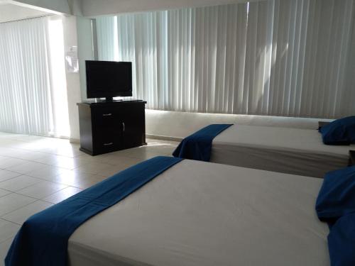 a hotel room with two beds and a flat screen tv at Posada San Cristobal in Cuernavaca