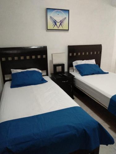 two beds in a room with blue and white sheets at Posada San Cristobal in Cuernavaca