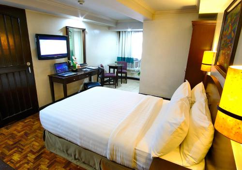 a hotel room with a bed and a desk at Fersal Hotel - Manila in Manila