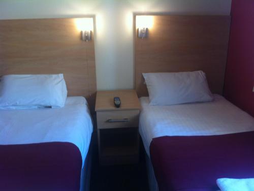 a hotel room with two beds and a night stand at City Inn Express Hotel in London