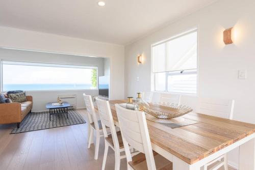 a dining room and living room with a table and chairs at Luxury house with Clifftop Seaview in Whangaparaoa
