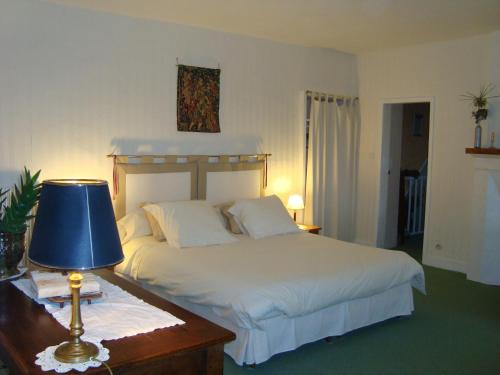 sypialnia z łóżkiem i stołem z lampką w obiekcie La Maison Claire w mieście Longueville