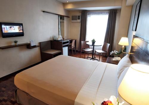 a hotel room with a bed and a desk at Fersal Hotel Kalayaan, Quezon City in Manila
