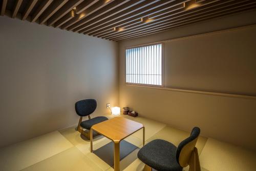 a room with two chairs and a table and a window at Tomoya Residence Hotel Kyoto in Kyoto