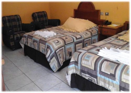two beds sitting next to each other in a room at Hotel Pasabien in Huité