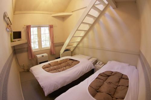 a room with two beds and a ladder on the wall at Hakuba Sun Valley Hotel in Hakuba