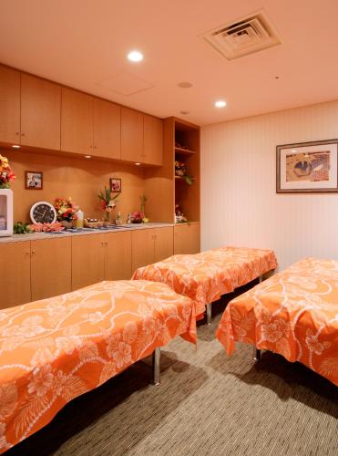 a room with three beds with orange sheets in it at Hotel Emion Tokyo Bay in Urayasu