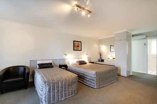 a hotel room with two beds and a television at Tamar River Villas in Launceston