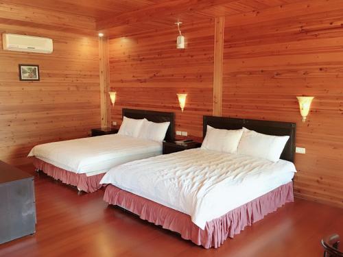 two beds in a room with wooden walls at Yuli Sun Homestay in Yuli