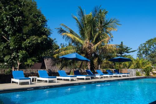 a row of blue chairs and umbrellas next to a swimming pool at Blue Marine Resort in Gili Air