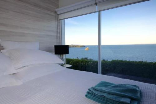 a bedroom with a bed with a view of the ocean at Luxury house with Clifftop Seaview in Whangaparaoa