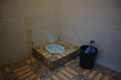 łazienka z wanną w wyłożonej kafelkami podłodze i koszem na śmieci w obiekcie Homestay Tanjung Duata Bohe Silian w mieście Maratua Atoll