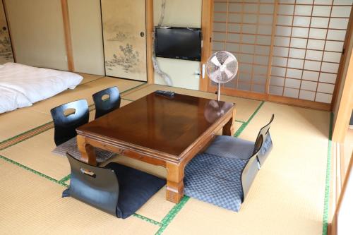 a room with a table and chairs and a fan at 一棟貸し平戸よこた in Hirado