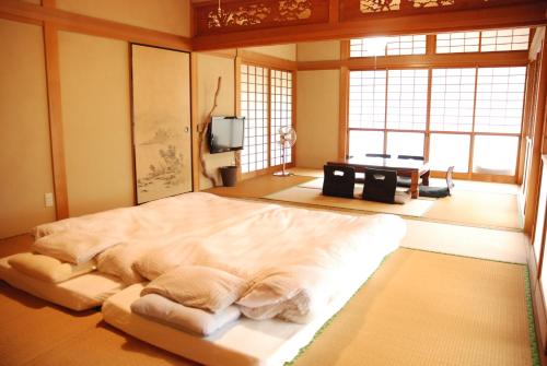 a bedroom with a large bed in a room with windows at 一棟貸し平戸よこた in Hirado