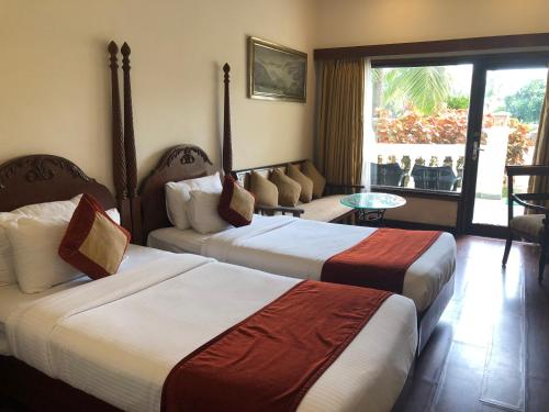 a hotel room with two beds and a balcony at The Hans Coco Palms in Puri