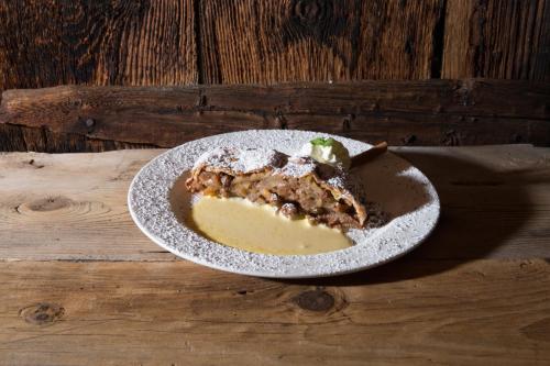 ein Stück Kuchen auf einem Teller auf einem Holztisch in der Unterkunft Hotel Baita Fiorita in Santa Caterina Valfurva