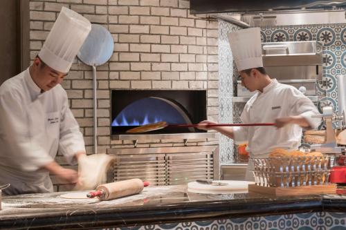 two chefs standing in a kitchen preparing food at Hyatt Regency Fuzhou Cangshan in Fuzhou