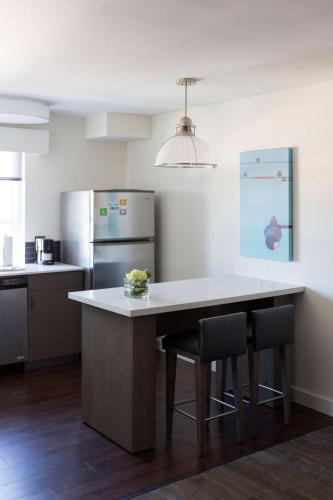a kitchen with a large white counter with two chairs at Hyatt House Charleston - Historic District in Charleston