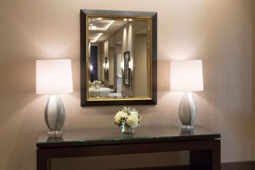 two lamps on a table with a mirror and flowers at Hyatt House Charleston - Historic District in Charleston