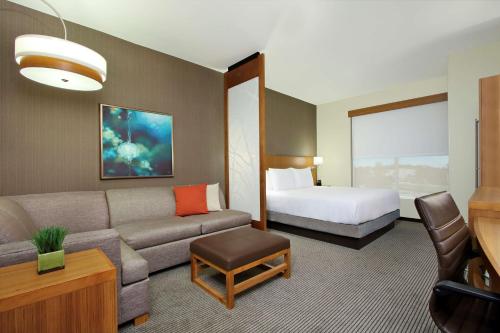 a hotel room with a couch and a bed at Hyatt Place Houston/Katy in Katy