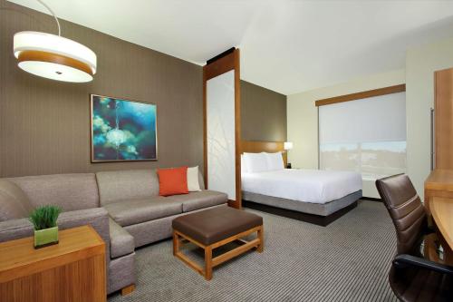 a hotel room with a couch and a bed at Hyatt Place Houston NW Vintage Park in Houston