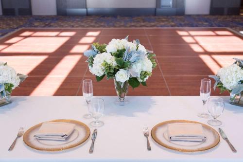 a table with two plates and a vase of flowers at Hyatt House Charleston - Historic District in Charleston