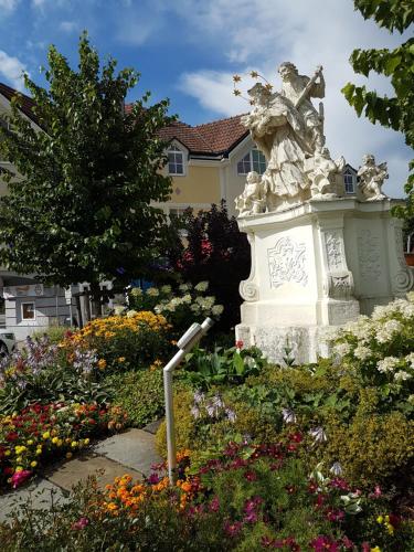 a statue in the middle of a garden with flowers at Apartment Nepomuk in Kirchberg an der Pielach