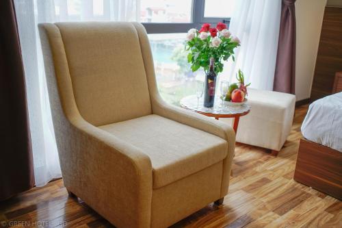 a chair in a room with a vase of flowers at Green Hadong Hotel in Hà Ðông