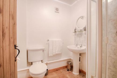 a white bathroom with a toilet and a sink at Highgate Annexe in Takeley