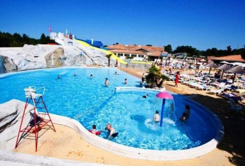 a group of people in a pool at a water park at La Palmyre - Les Mathes - Mobil home 3 ch LUXUEUX de 40m2 - Grand emplacement dans village loisirs 4 étoiles - "les Charmettes 394" proche FUN ZONE in Les Mathes