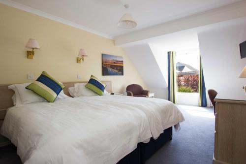 een slaapkamer met een groot wit bed met 2 kussens bij Beausite Hotel in Grouville