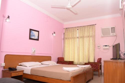 a bedroom with two beds and a pink wall at Margao Residency in Madgaon