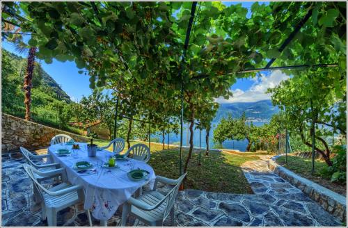 a table and chairs under a tree with a view at Fantastica Casa Poppo in Bellano