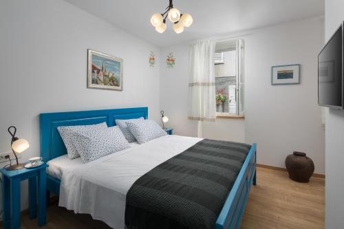 a bedroom with a blue and white bed and a television at Mondinica Heritage House - Heated pool in Dobrinj