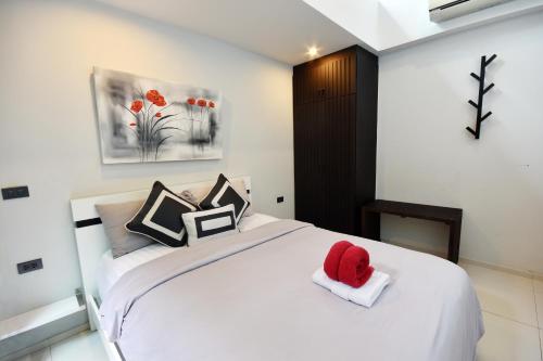 a bedroom with a white bed with a red hat on it at Villa Labaron in Koh Samui 