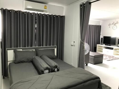 a bedroom with a bed with gray sheets and curtains at T11 Popula Condo by Prathomlerk in Pak Kret