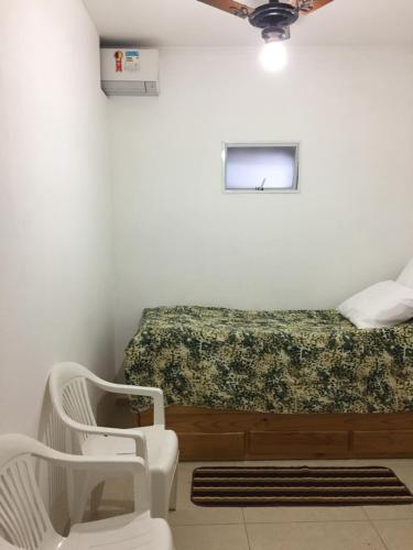 a room with a bed and two white chairs at Apartamento José Menino in Santos