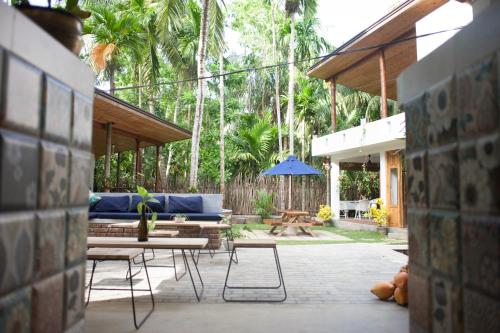 a patio with a blue couch and tables and trees at Salt House in Hiriketiya