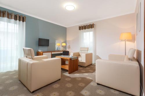 a living room with white chairs and a table at Best Western Hotel Jurata in Jurata