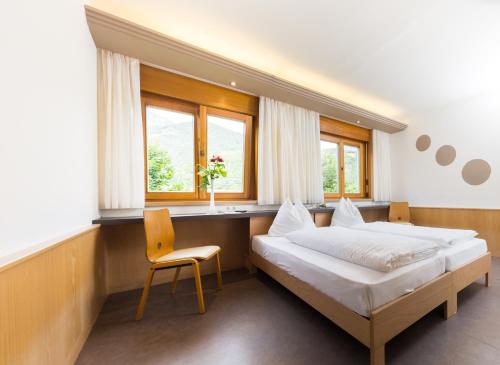 a bedroom with a bed and a desk and a chair at Pension Lichtenburg in Nalles