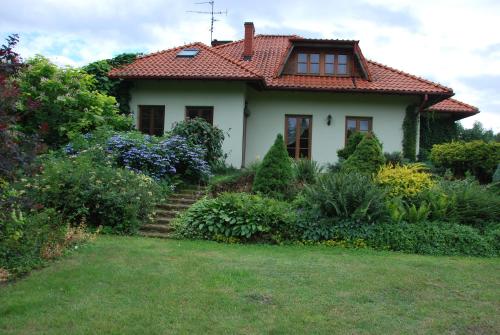 a small white house with a red roof at Pensjonacik Ogrody in Pierzchno