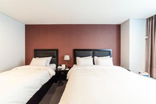 two beds in a hotel room with white sheets at Gangneung Tourist Hotel in Gangneung