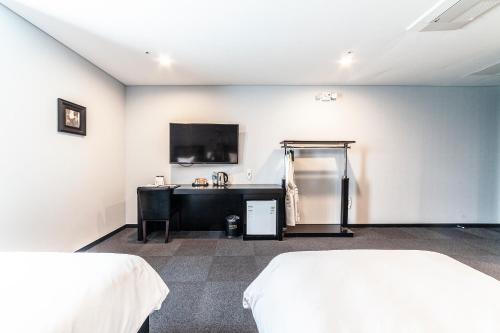 a room with two beds and a tv on the wall at Gangneung Tourist Hotel in Gangneung