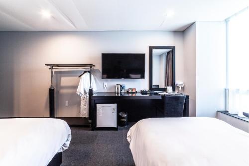 a hotel room with two beds and a television at Gangneung Tourist Hotel in Gangneung