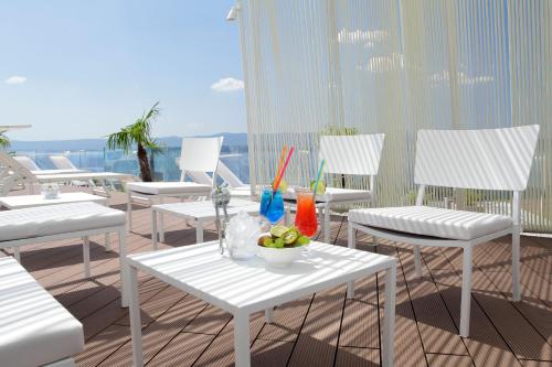 a balcony with white chairs and a table with a bowl of fruit at Lifestyle Hotel Vitar - Adults Only in Bol