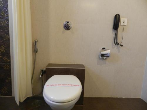 a bathroom with a toilet with a phone on the wall at Hotel K Square in Kolhapur