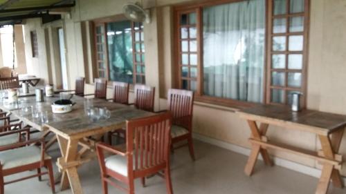 une salle à manger avec des tables et des chaises en bois ainsi que des fenêtres dans l'établissement Tranquil Treasure, à Panchgani