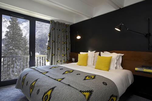 a bedroom with a bed with yellow pillows and a window at Totem, Friendly Hotel & Spa in Flaine