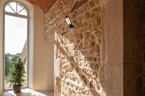 a room with a stone wall with a light and a window at L'hôtel du Couvent in Vagnas